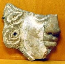 Màscara de terracota. Ex-vot trobat al temple de la part alta del Puig de Sant Andreu. Representa un personatge mitològic (Gorgona, Aquelous), una cara femenina o demoníaca. Segle III aC